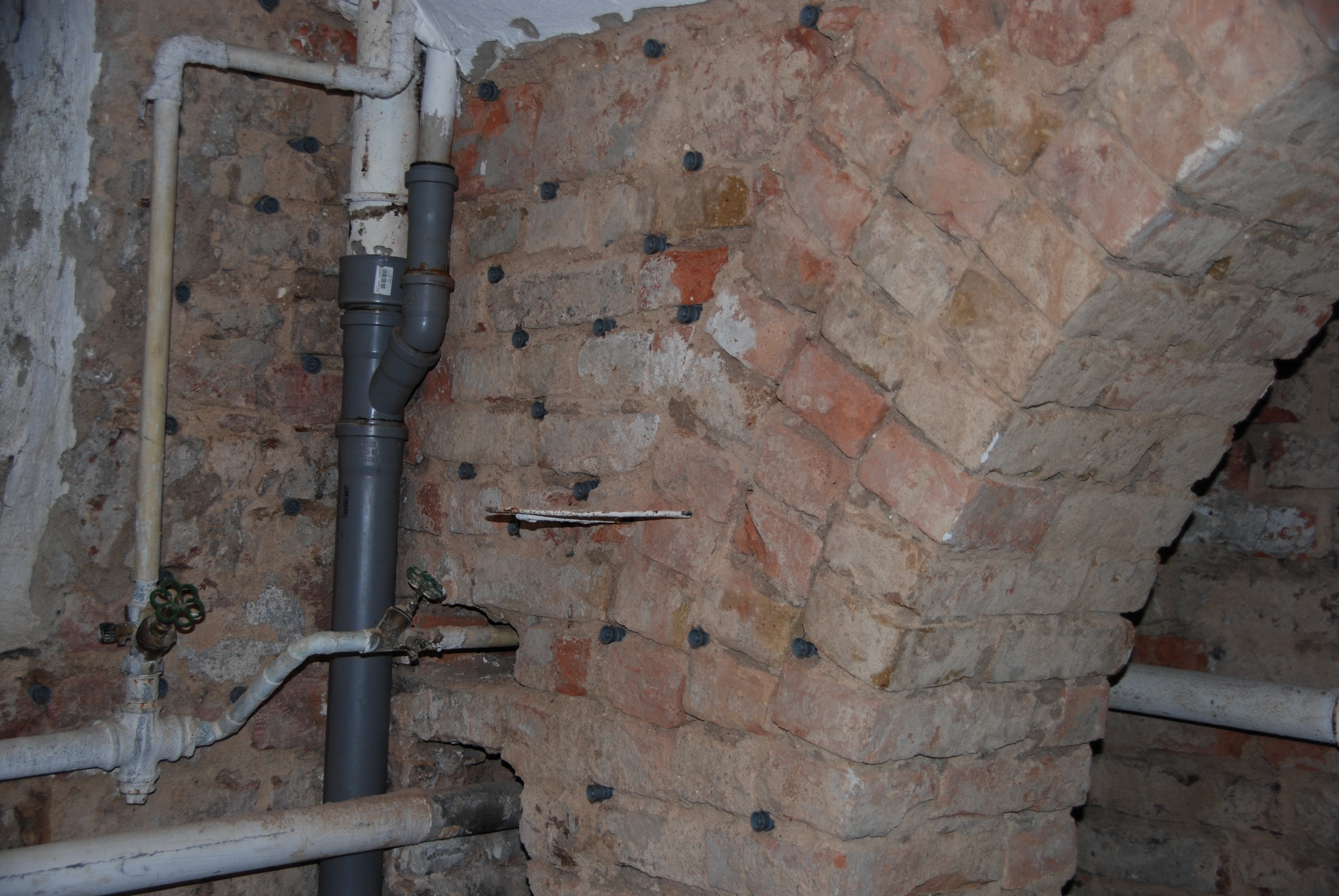 Mauerwerk eines Kellergewölbes mit vielen kleinen und regelmässigen Bohrungen in dem sich fungizide Injektionen befinden.